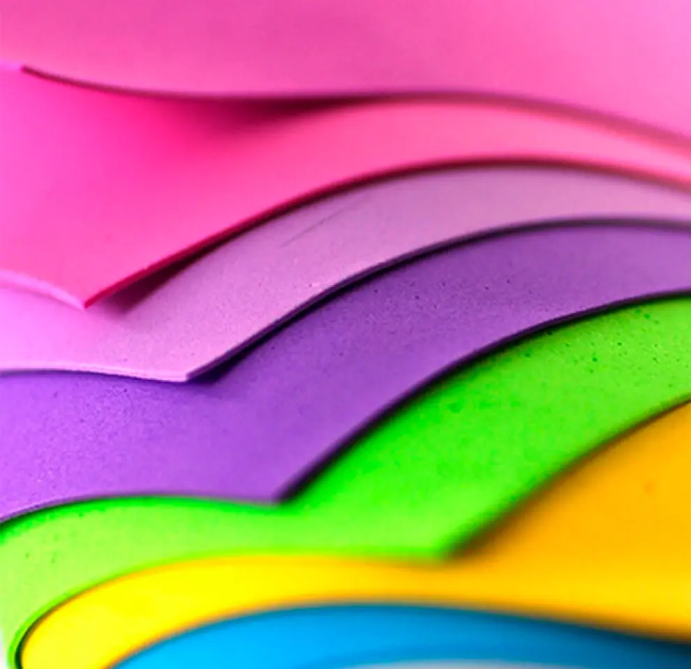 Stacked sheets of vibrant, multi-colored foamiran material in shades of pink, purple, green, and yellow